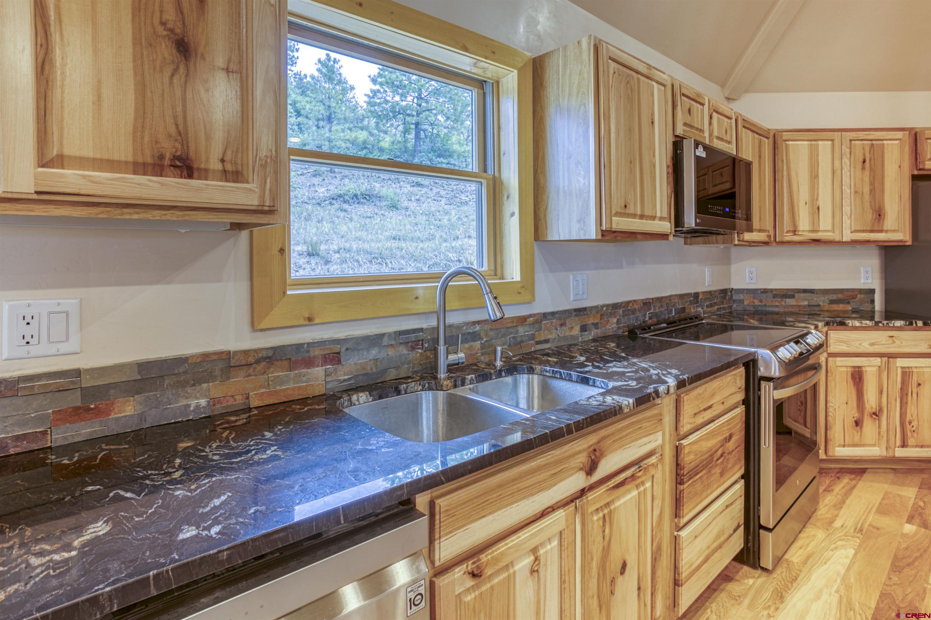 159 Snow Circle Pagosa Springs, CO 81147 - Photo 17 of 45 a kitchen with granite countertop a sink a stove and cabinets