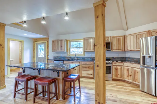 a kitchen with stainless steel appliances kitchen island granite countertop a table chairs and a refrigerator