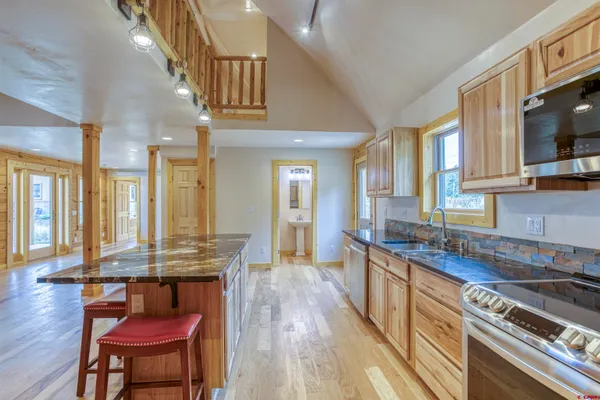 a kitchen with stainless steel appliances granite countertop a stove a sink dishwasher and cabinets with wooden floor