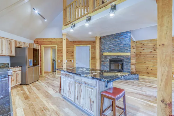 a open kitchen with granite countertop a stove top oven a sink dishwasher and a fireplace with wooden floor