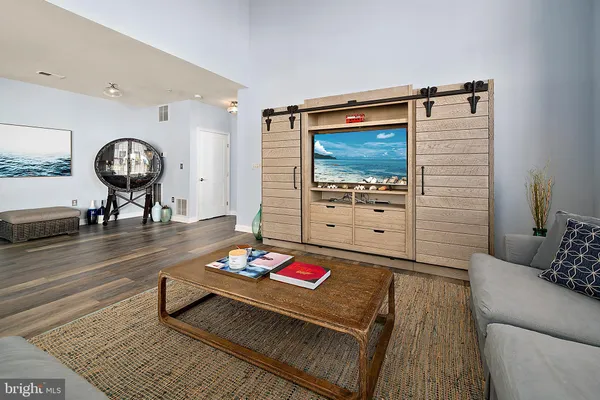 a living room with furniture kitchen view and a wooden floor