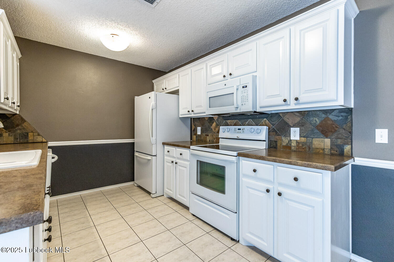 6120 7th Drive Lubbock, TX 79416 - Photo 12 of 33 a kitchen with granite countertop white cabinets and stainless steel appliances