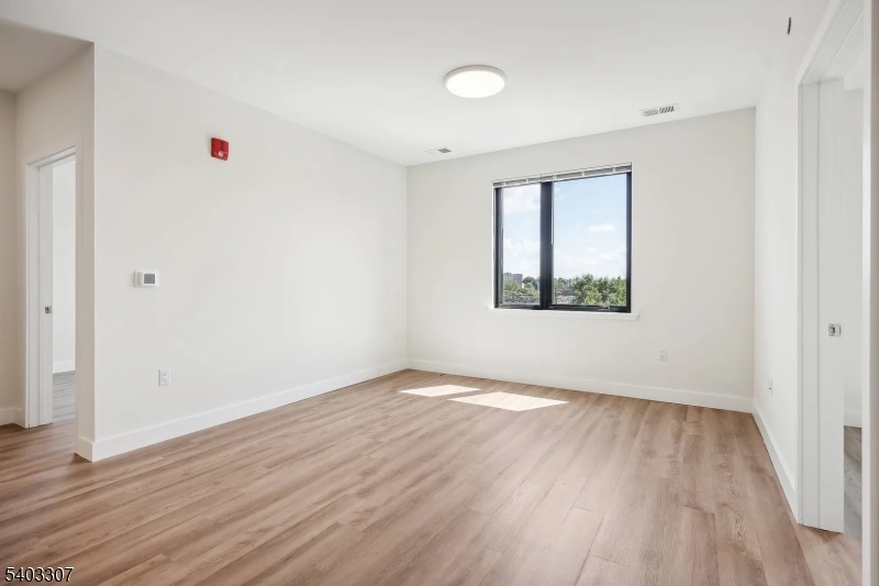 49 South Day Street, Unit 316 Orange, NJ 07050 - Photo 11 of 26 an empty room with wooden floor and windows