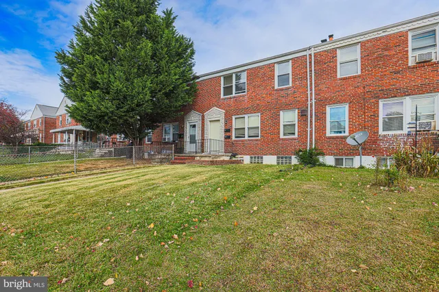 a view of a brick house with a yard and plants