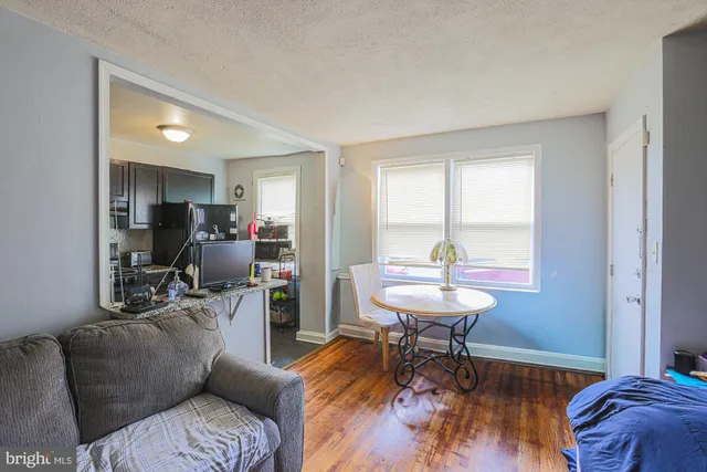 a living room with furniture and a dining table with wooden floor