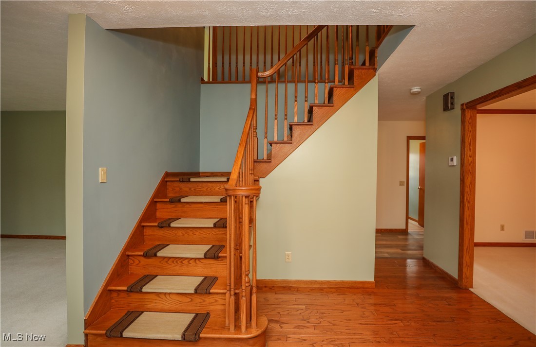 12565 Alpha Road Hiram, OH 44234 - Photo 22 of 50 Staircase with visible vents, a textured ceiling, baseboards, and wood finished floors