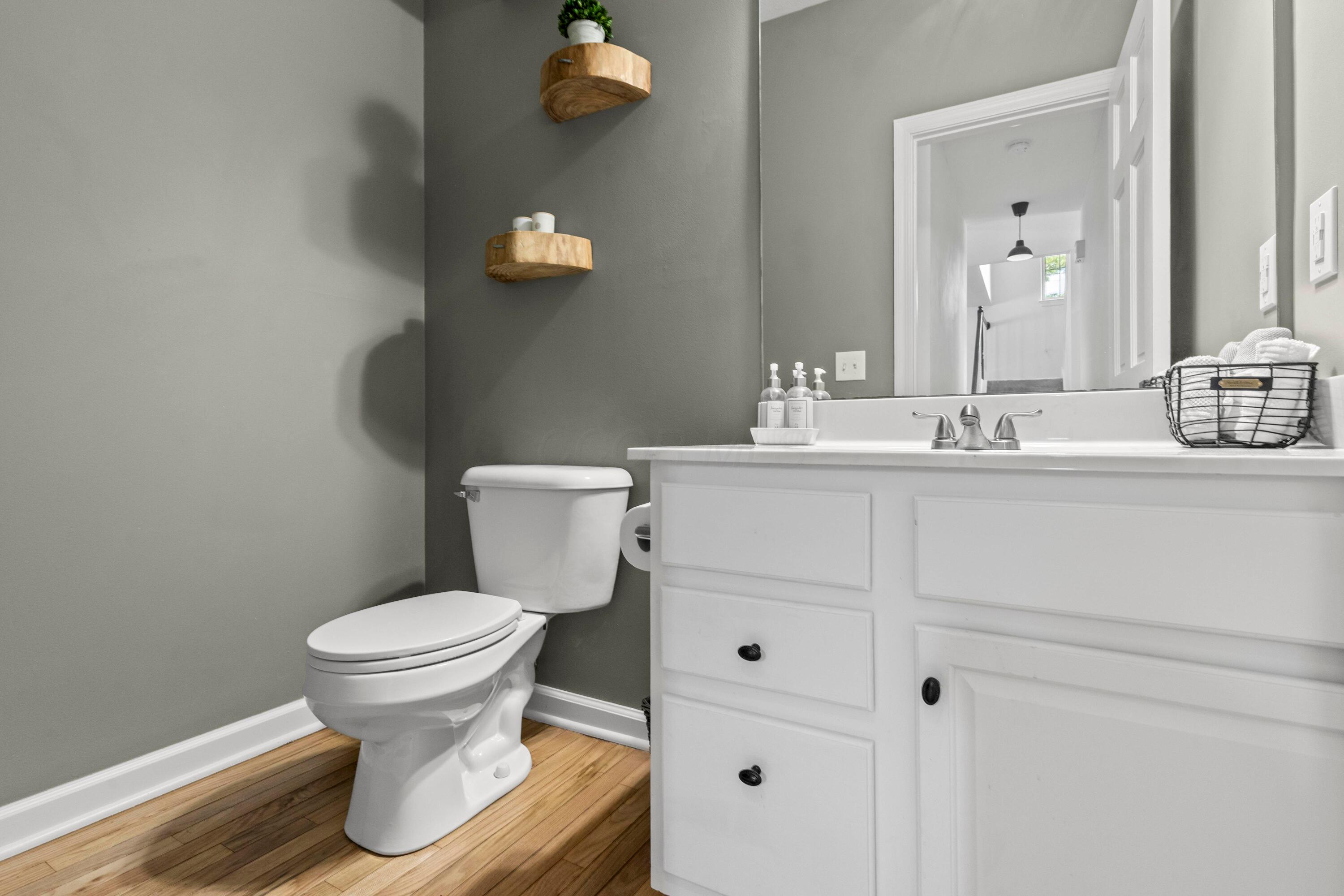 1515 Dale Ford Road Delaware, OH 43015 - Photo 15 of 74 • Hardwood flooring • Grey painted walls • Enclosed vanity with single bowl, cultured marble sinktop • Floating shelves remain • 2 bulb wall light • Ceiling exhaust
