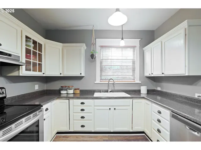 a kitchen with granite countertop a sink stainless steel appliances and cabinets