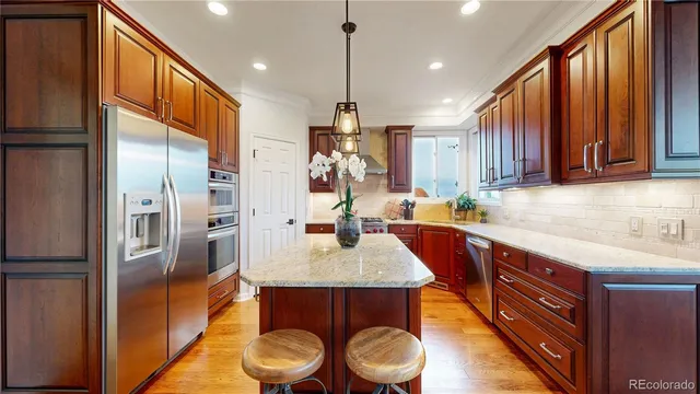 a kitchen with kitchen island a counter top space a sink a refrigerator and wooden floor
