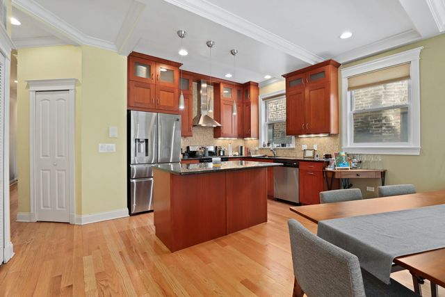 a kitchen with stainless steel appliances granite countertop a refrigerator a sink dishwasher a stove and a dining table with wooden floor