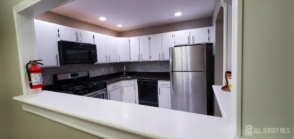 a kitchen with kitchen island granite countertop stainless steel appliances and refrigerator