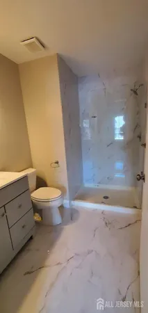 a bathroom with a granite countertop toilet and a sink
