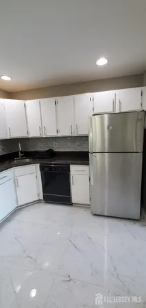 a kitchen with a refrigerator a sink and white cabinets