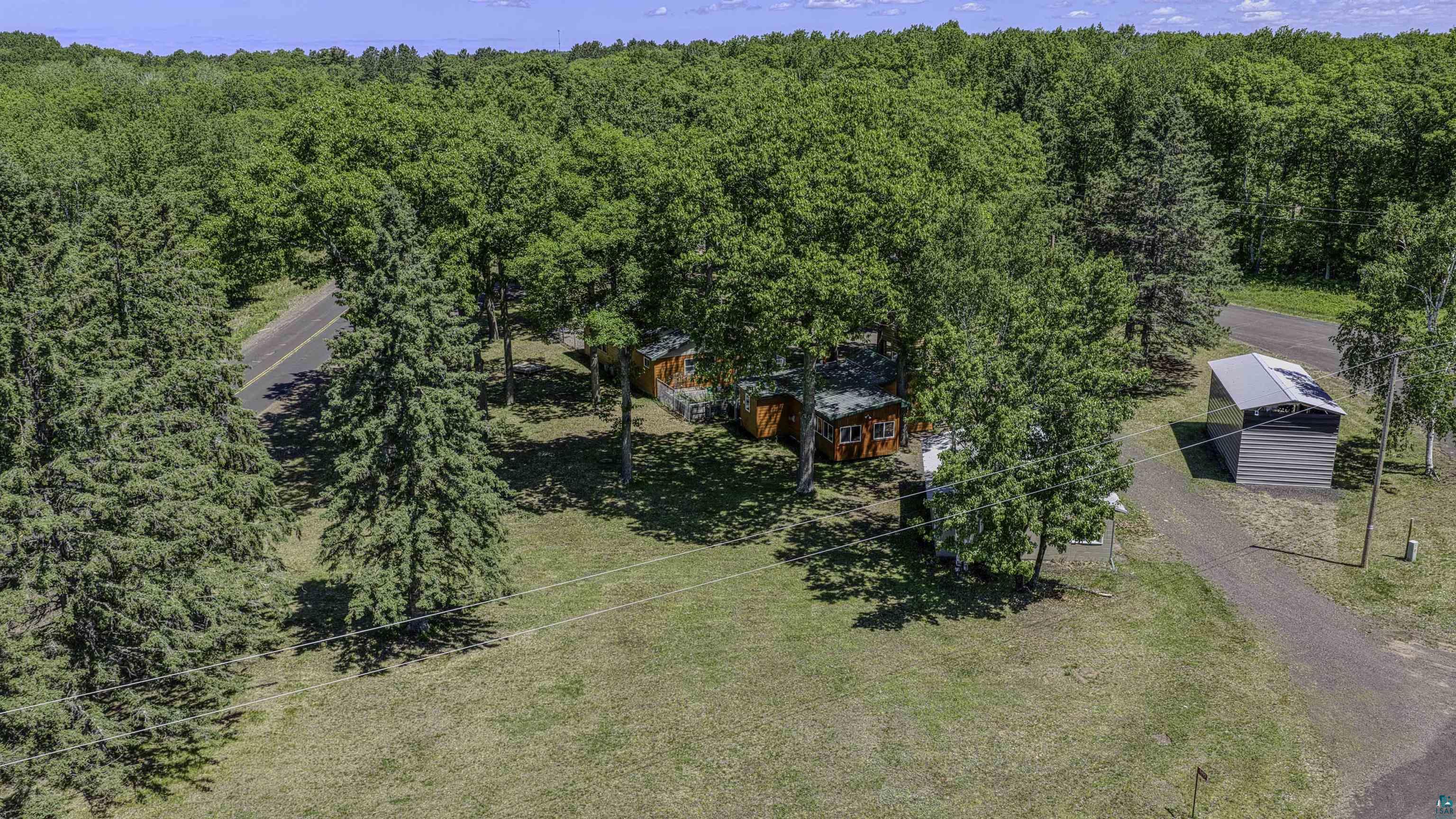 66075 Rooster Road Iron River, WI 54847 - Photo 2 of 52 Expansive property featuring mature trees, a cabin-style structure with a dark roof, and a contemporary gray outbuilding with a metal roof
