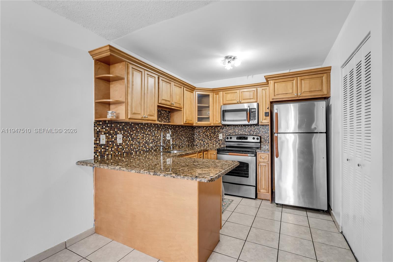 1750 West 56th Street, Unit 210 Hialeah, FL 33012 - Photo 4 of 22 a kitchen with stainless steel appliances granite countertop a refrigerator and a stove top oven