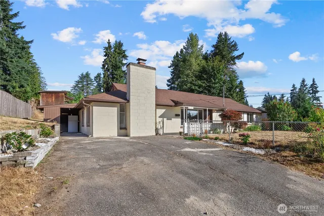 a big house with large trees and wooden fence