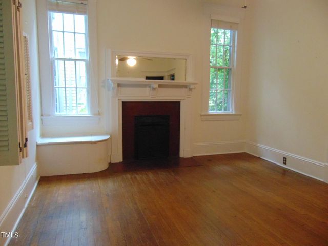 an empty room with wooden floor closet and windows