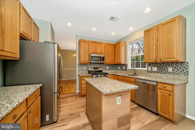 a kitchen with stainless steel appliances granite countertop wooden cabinets a sink and a stove