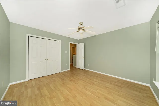 a view of an empty room with wooden floor and a ceiling fan