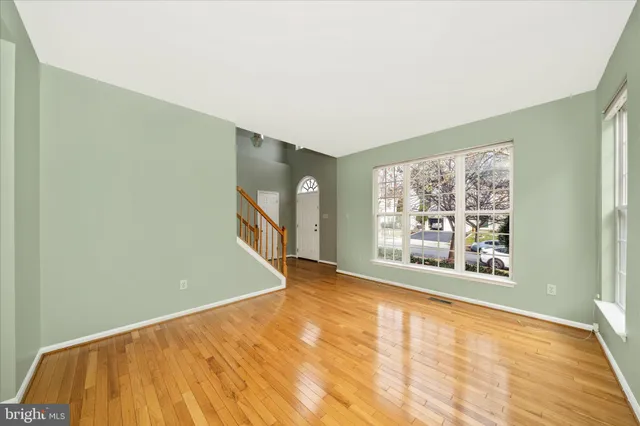 a view of an empty room with window and wooden floor