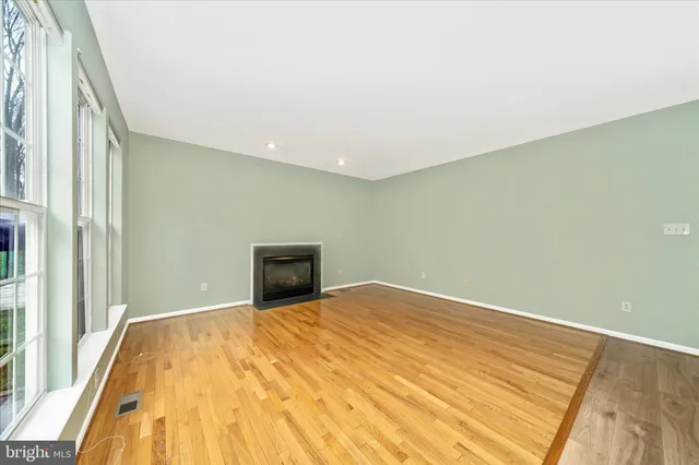 a view of a big room with wooden floor and windows