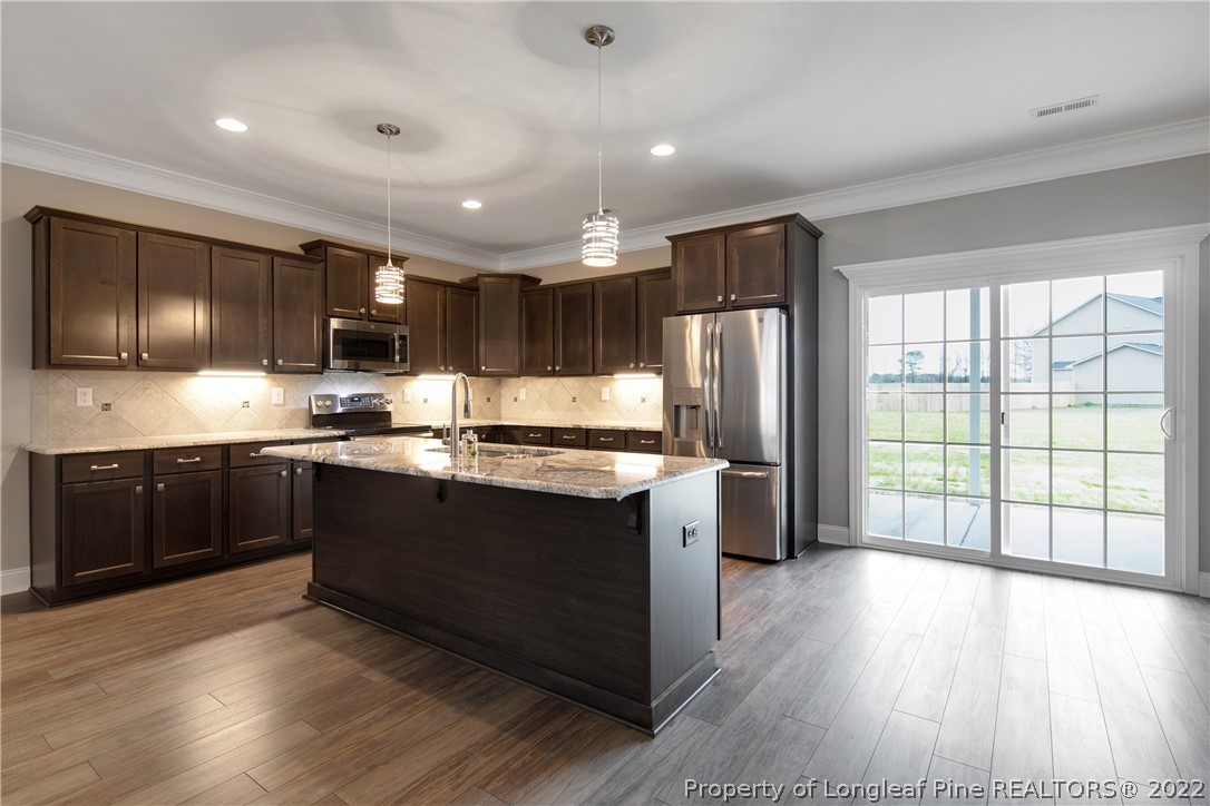 2643 Riddle Farm Hope Mills, NC 28348 - Photo 12 of 50 a kitchen with stainless steel appliances granite countertop a refrigerator a sink dishwasher a stove and a oven with wooden floor