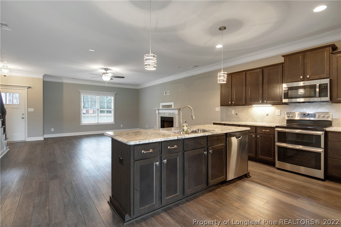 2643 Riddle Farm Hope Mills, NC 28348 - Photo 15 of 50 a kitchen with stainless steel appliances granite countertop a stove a sink dishwasher and a microwave oven with wooden floor