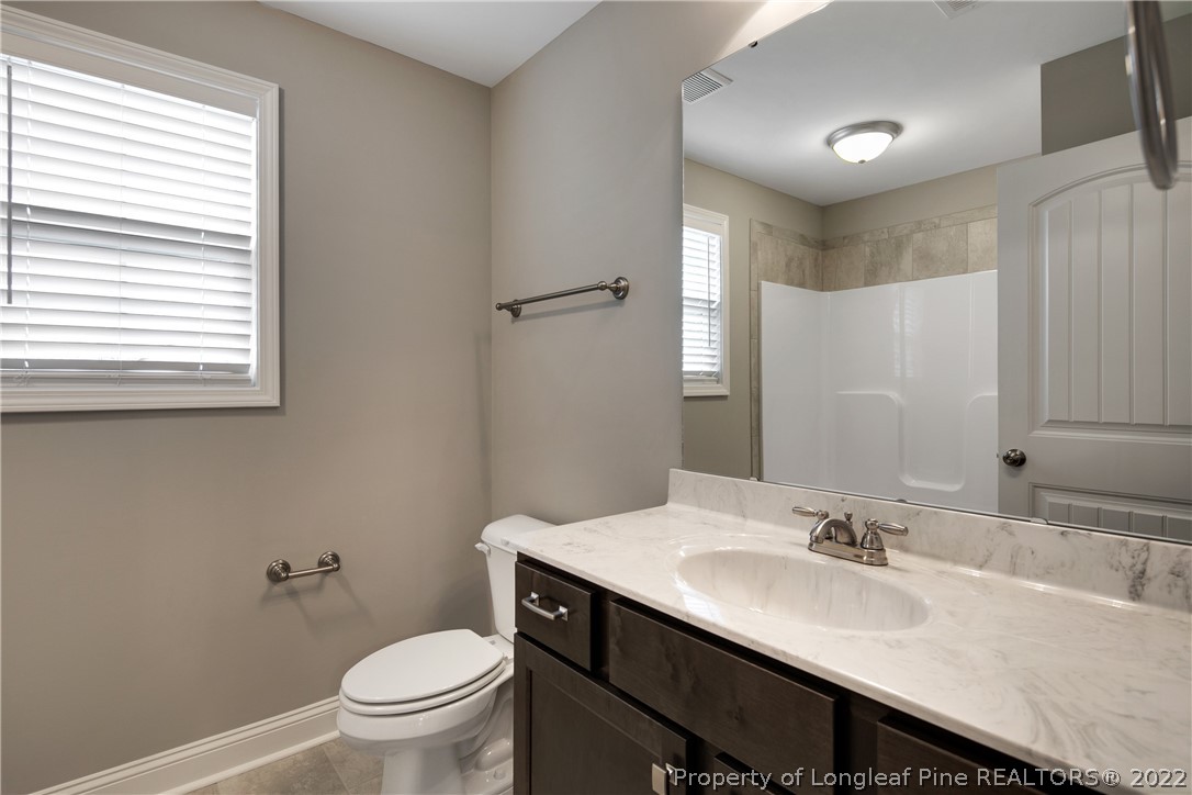 2643 Riddle Farm Hope Mills, NC 28348 - Photo 43 of 50 a bathroom with a granite countertop sink toilet a large mirror and a window