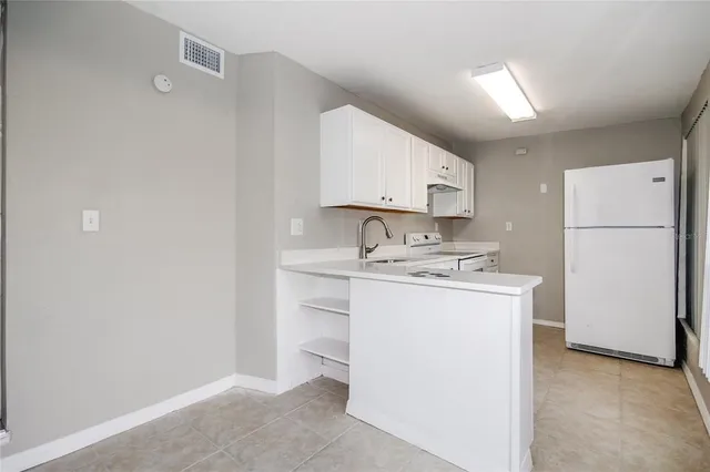 a kitchen with a sink a stove a refrigerator and white cabinets