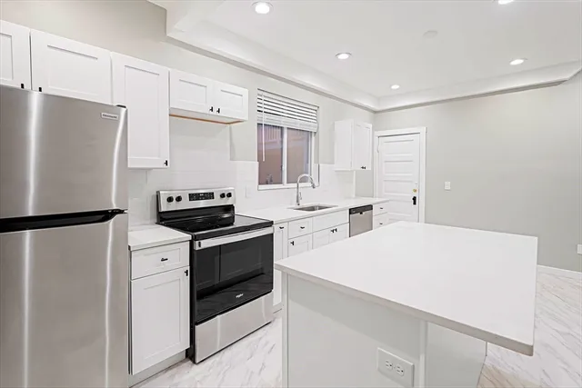 a kitchen with a white stove refrigerator and white cabinets