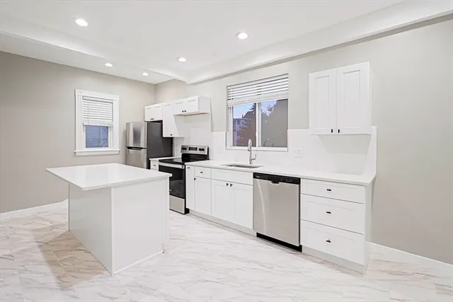 a kitchen with white cabinets and appliances