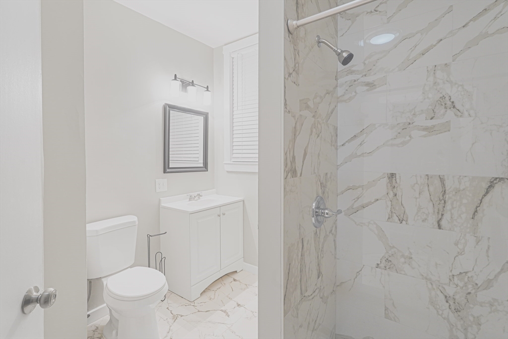 381 Adams Street, Unit 2 Boston, MA 02122 - Photo 9 of 42 a bathroom with a toilet sink and shower curtain