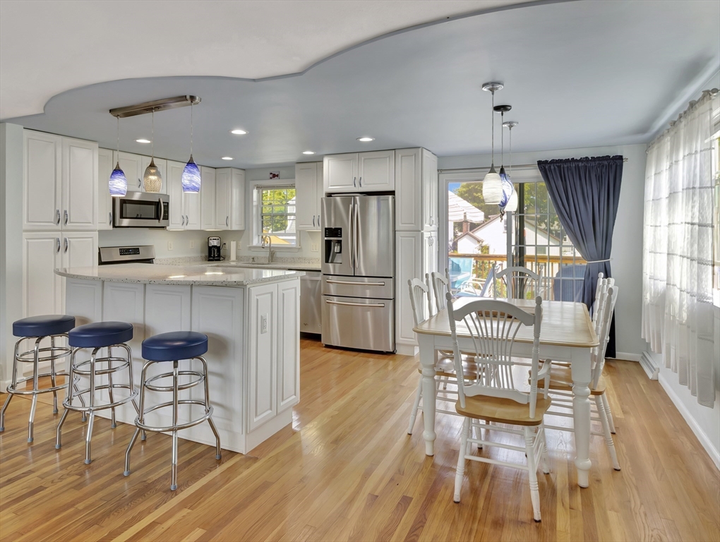 15 H Street Hull, MA 02045 - Photo 15 of 35 a kitchen with stainless steel appliances a dining table chairs refrigerator and sink