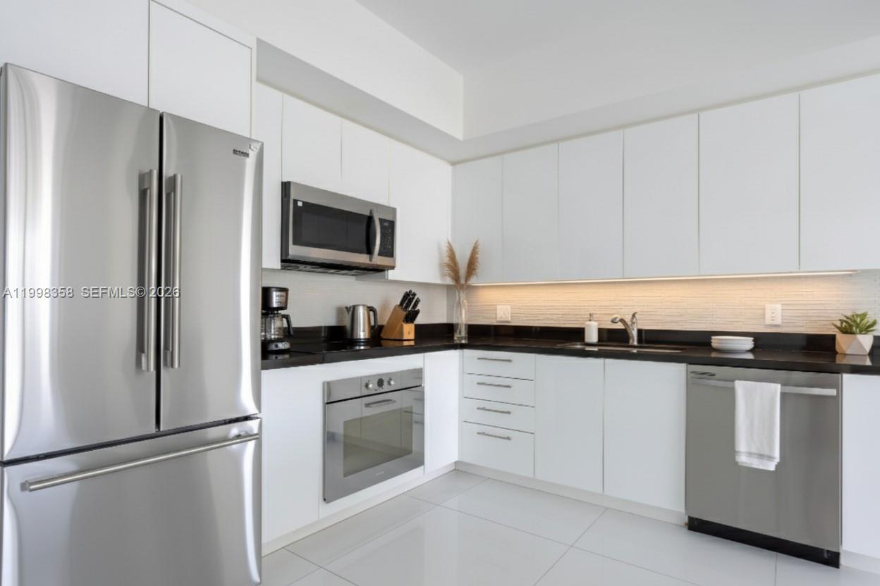 92 Southwest 3rd Street, Unit 3512 Miami, FL 33130 - Photo 3 of 67 a kitchen with stainless steel appliances granite countertop a refrigerator a stove a sink and white cabinets