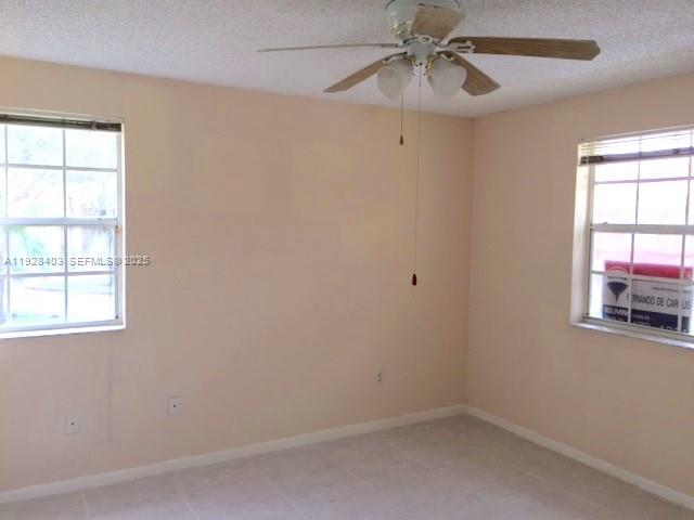 18324 Northwest 68th Avenue, Unit H Hialeah, FL 33015 - Photo 6 of 15 an empty room with a window and chandelier fan