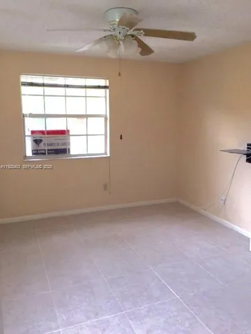 en empty room with windows and chandelier fan