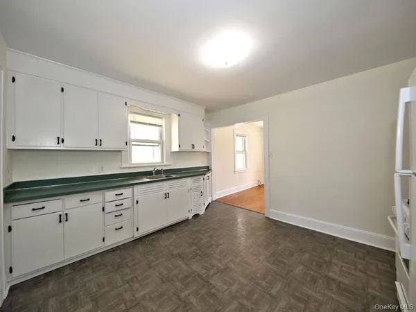 a kitchen with granite countertop white cabinets white appliances and a wide window