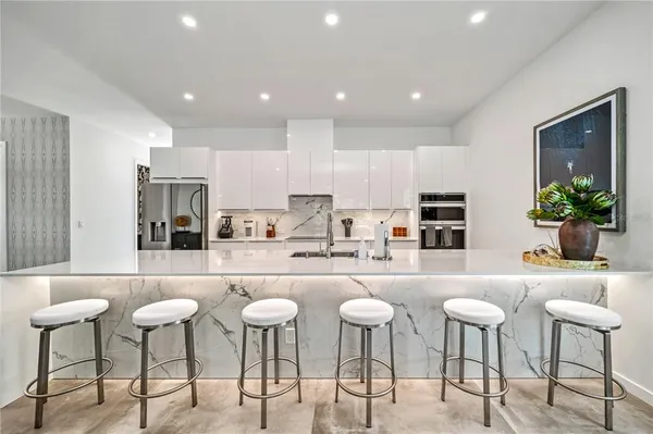 a kitchen with a dining table chairs stove and white cabinets