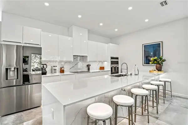 a kitchen with stainless steel appliances kitchen island granite countertop a sink a stove a dining table and chairs