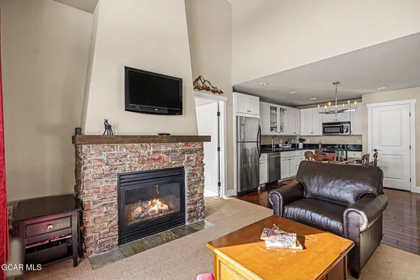 a living room with stainless steel appliances furniture a fireplace a flat screen tv and a fireplace
