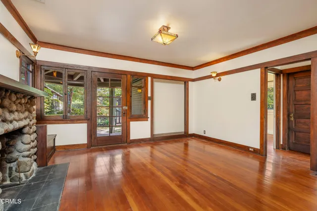 a view of an empty room with wooden floor fireplace and a window