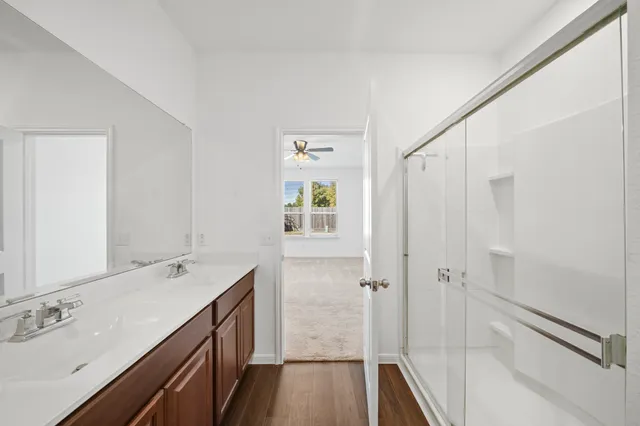 a bathroom with a double vanity sink a toilet and shower