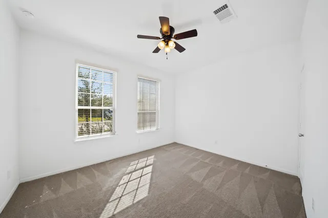 an empty room with a ceiling fan and window