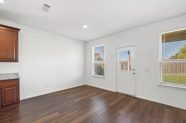 a view of an empty room with wooden floor and a window