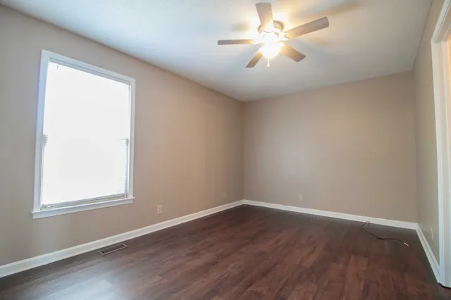 an empty room with a window and a fan