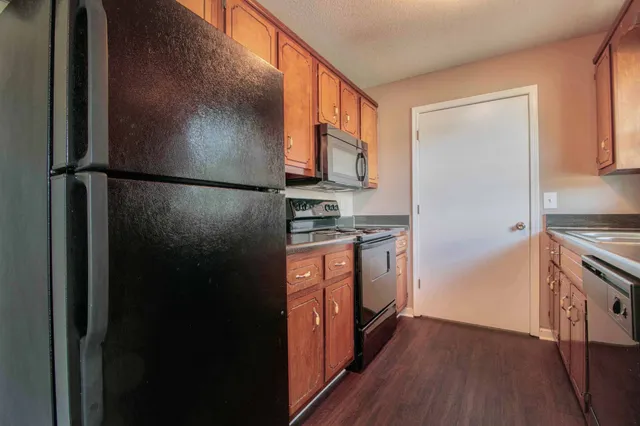 a kitchen with stainless steel appliances granite countertop a refrigerator a stove a sink and dishwasher with wooden floor