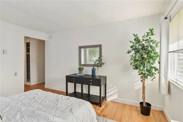 a bedroom with a bed table chair and a window