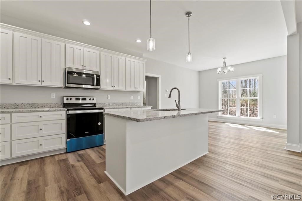 2148 Sandy Hook Road Goochland, VA 23063 - Photo 11 of 34 a kitchen with granite countertop a stove a sink and white cabinets with wooden floor