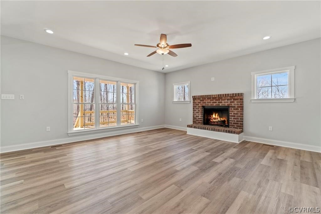 2148 Sandy Hook Road Goochland, VA 23063 - Photo 5 of 34 an empty room with windows a fireplace a ceiling fan and wooden floor