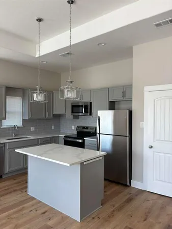 a kitchen with a refrigerator a sink and dishwasher with wooden floor